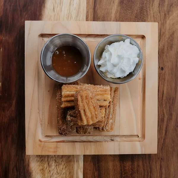 Don Bravo Mexican Grill churros with caramel and whipped cream on a wooden tray.