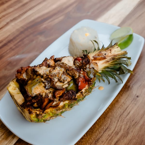 Don Bravo's pineapple fajita, a halved pineapple filled with grilled meat, peppers, and cheese, served with rice and lime.