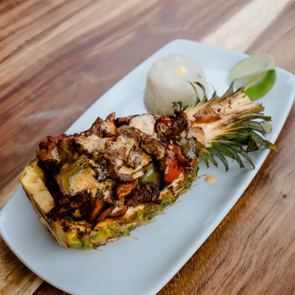 Don Bravo's pineapple fajita, a halved pineapple filled with meat, peppers, and cheese, with rice and lime.
