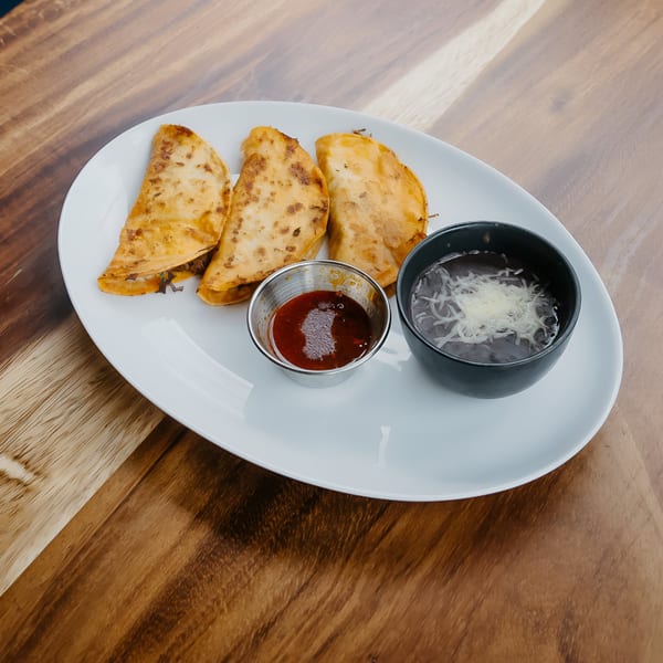 Three golden-brown quesadillas, a side of red salsa, and a bowl of black beans with cheese.